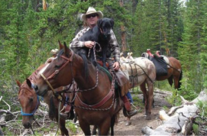 Jeff Smith on horseback with his dog Colt. 