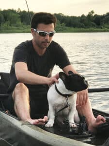 A man and a small dog in a kayak on the water.